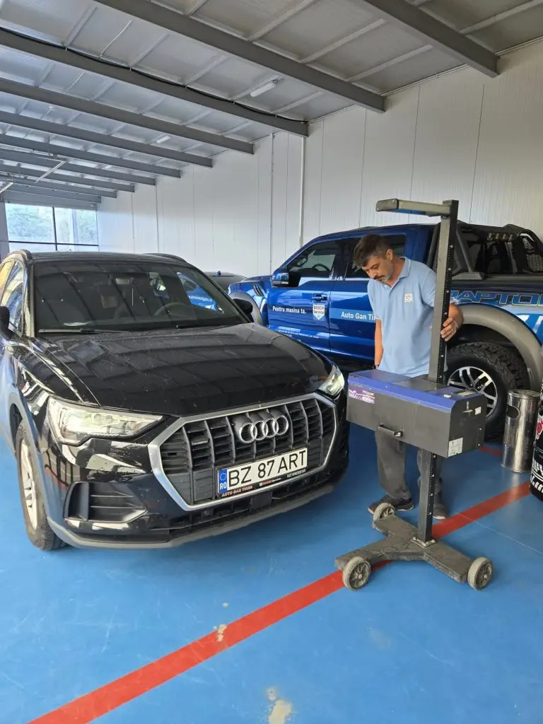 Autoturism Audi și tehnician lângă aparatul de verificare a farurilor în stația Auto Gan