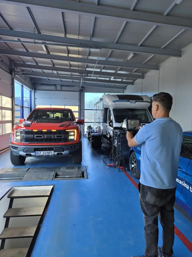 Tehnician și vehicule pe linia de inspecție a stației Auto Gan